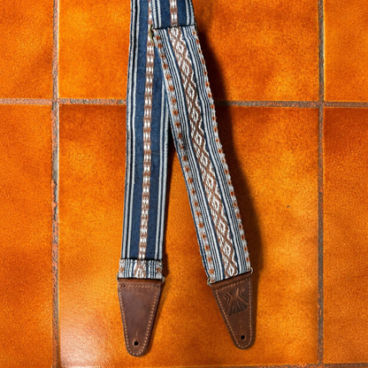 La Tierra handwoven Maya guitar strap — indigo, cream, and rust stripe weave with full-grain leather ends and brass hardware