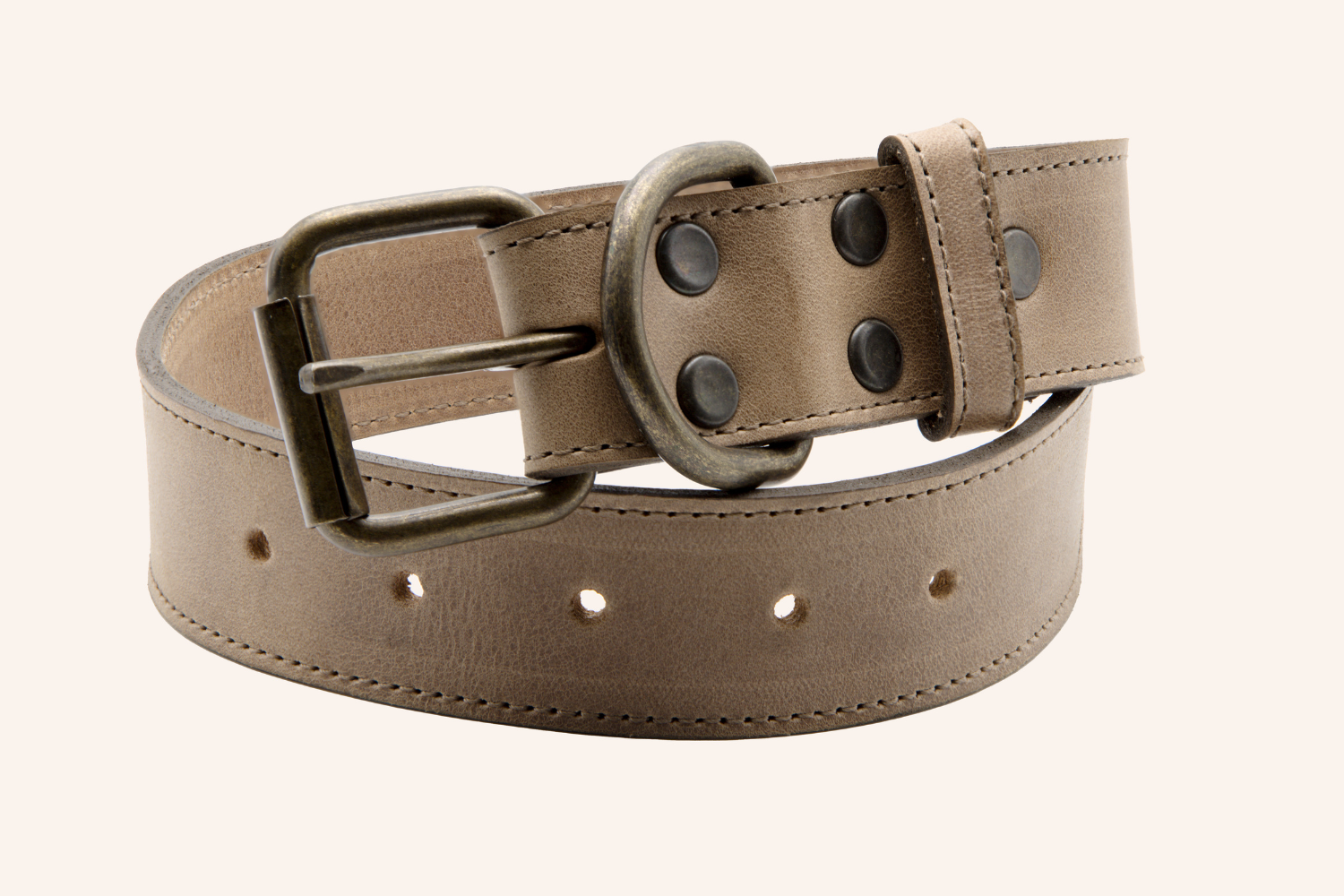 A tan leather dog collar coiled up, displaying antique brass hardware, double rivets, and a D-ring for attaching a leash.