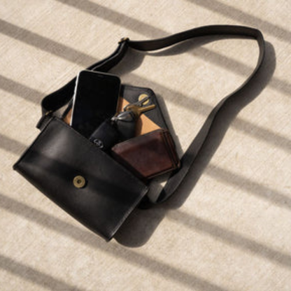 Antigua Threads Everywhere Crossbody Bag in black full-grain leather — open showing phone, wallet, keys, and sunglasses fitting inside