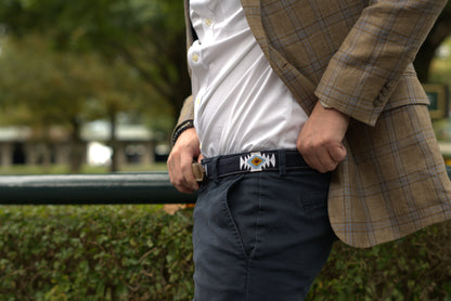 Person wearing a tan plaid blazer and blue pants, showcasing a handwoven blue belt with white, yellow, and turquoise geometric patterns by Antigua Threads