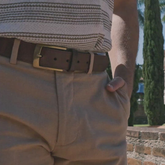 Cobán handwoven Maya belt worn by a model in khaki pants and striped shirt — cream and cobalt blue stripe pattern in an outdoor setting
